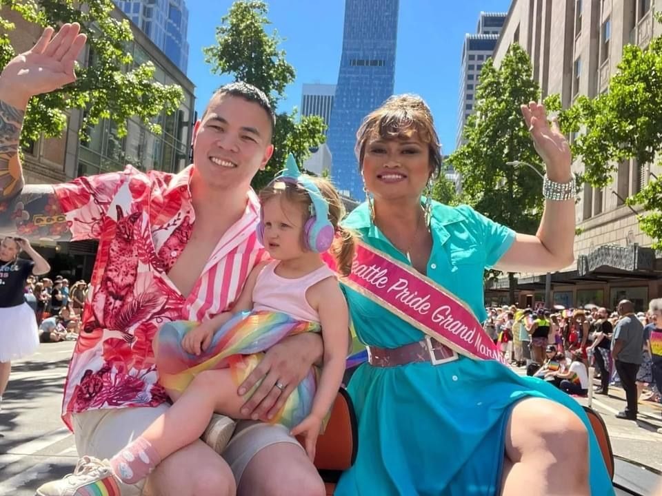 Gaysha Starr waving during a parade while wearing a Grand Marshal sash
